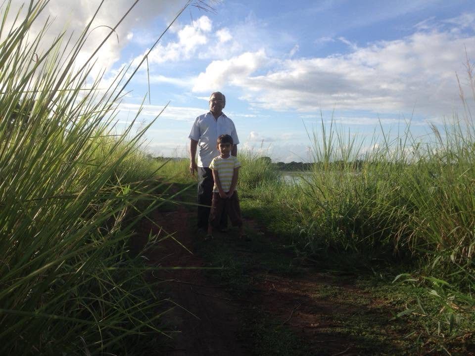 Grandfather and grandson on a field bund by the water
